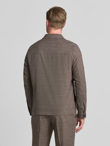Männermodel trägt Hemdjacke mit Brusttaschen von MCNEAL in Braun, mit Material-Mix mit Viskose-Anteil, Gerader-Schnitt, Rückenlänge 70 cm, Ganzkörperansicht Rückansicht.