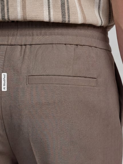 Männermodel trägt Relaxed Fit Sweatpants mit Viskose-Anteil von Lindbergh in Hellbraun, feine Struktur, Detailaufnahme Rückenansicht. Elastischer Bund, dezente Bügelfalte, elastischer Material-Mix laut Kontext.