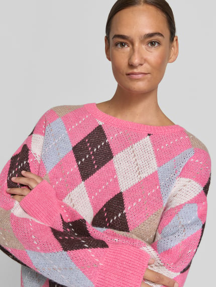 Kobiece model prezentuje sweter z dzianiny 'Strickpullover im Allover-Look' od Milano Italy, Mieszanka materiałów z alpaka, krój relaxed fit, wzór na całej powierzchni, okrągły dekolt, długość tyłu w rozmiarze S 52 cm, długość rękawów w rozmiarze S 52 cm, pastelowe kolory, diamentowe wzory, miękka tekstura, zbliżenie na górną część ciała.