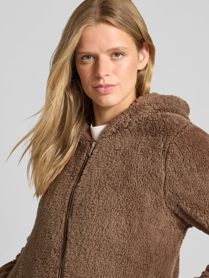 Frauenmodel trägt Regular Fit Teddyjacke mit Kapuze Modell 'NEWANNA' von ONLY, braune, flauschige Textur, Nahaufnahme Oberkörper, Damen Sweatjacke von ONLY