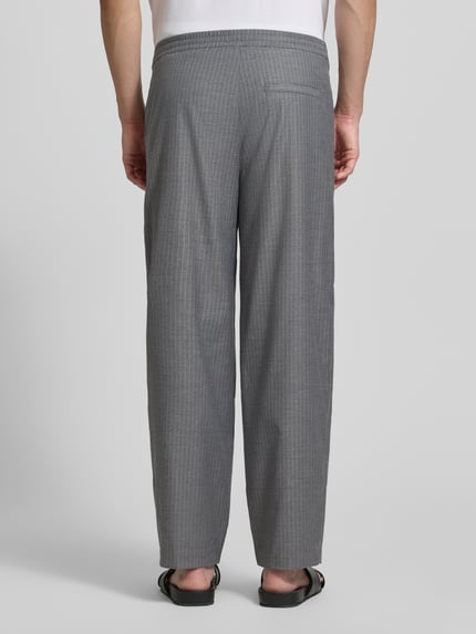 Männermodel trägt graue Herren Jog Pants mit französischen Eingrifftaschen Modell 'YROWAY' von American Vintage, Material-Mix mit Viskose-Anteil, Straight Fit, elastischer Bund, Gesäßleistentasche, feine Streifenstruktur, Ganzkörperansicht Rückansicht.