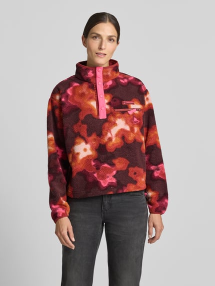Kobiece model nosi Fleeceshirt mit Stehkragen und Label-Patch Modell 'Helvetia II' od Columbia w kolorach czerwonym, różowym i czarnym, prosty krój, Polar, Brustasza z zamkiem błyskawicznym, naszywka z logo, Długość tyłu w rozmiarze S: 57 cm, szerokość ramion w rozmiarze S: 48 cm, szerokość klatki piersiowej w rozmiarze S: 54 cm, długość rękawów w rozmiarze S: 59 cm, Ganzkörperansicht z przodu.