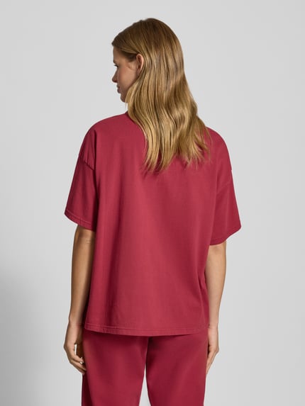 Frauenmodel trägt Oversized T-Shirt mit Logo Modell 'BRACY' von Pegador aus reiner Baumwolle in Rot, Rückansicht, Ganzkörperansicht.
