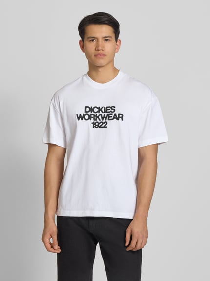 Męski model nosi T-Shirt mit Label-Print Modell 'TORREY' von Dickies z bawełny, krój regular fit, okrągły dekolt, długość tyłu w rozmiarze M 70 cm, widok z przodu całej sylwetki.