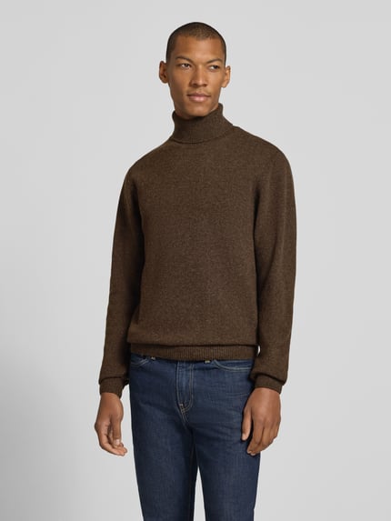 Męski model nosi Slim Fit Rollkragenpullover aus Woll-Mix Modell 'Karl' von Casual Friday w kolorze brązowym, prążkowane wykończenia, długie rękawy, prążkowany kołnierz, długość tyłu w rozmiarze M: 70 cm, długość rękawów w rozmiarze M: 69 cm, Ganzkörperansicht von vorne.