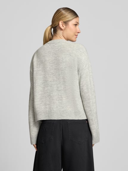 Frauenmodel trägt Cardigan mit aufgesetzten Taschen von Christian Berg Woman in unifarbener Strickoptik mit Struktur, Ganzkörperansicht Rückansicht.