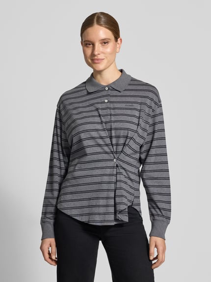 Frauenmodel trägt Relaxed Fit Poloshirt aus reiner Baumwolle von Closed, grau mit feinen Streifen, Raffungen, Logo-Print, Ganzkörperansicht von vorne.