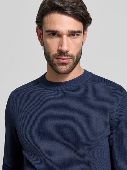 Mannelijk model draagt Slim Fit Pullover in breilook model 'Nordin' van Casual Friday in effen donkerblauw katoen, close-up bovenlichaam.