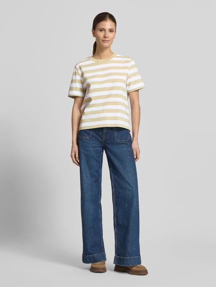 Frauenmodel trägt Boxy Fit T-Shirt aus reiner Baumwolle Modell 'ESSENTIAL' von Selected Femme, gelb-weiß gestreift, heavy Jersey, Rundhals, kurzarm, Ganzkörperansicht von vorne.