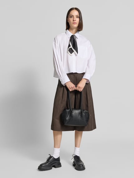 Frauenmodel trägt Satchel Bag mit Label-Prägung Modell 'KAYLA' von LIEBESKIND BERLIN in Schwarz, glatte Struktur, Ganzkörperansicht von vorne. Hauptfach mit Zweiwege-Reißverschluss, lange Tragegriffe, Reißverschlusstasche innen, 25 x 17 x 10 cm, Schulterriemen 70 cm.