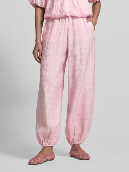 Frauenmodel trägt Stoffhose mit elastischem Bund von Jake*s Casual, lockerer Schnitt, Gesäßtaschen, rosa Farbton, Nahaufnahme Unterkörper.