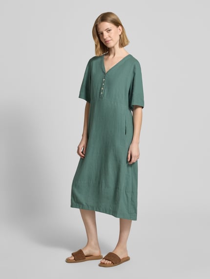 Modelka kobieca nosi knielanges Kleid aus Leinen-Viskose-Mix Modell 'Lava' von FREE/QUENT, kolor zielony, A-linia, V-dekolt, długość do kolan, guziki, tekstura gładka, długość tyłu w rozmiarze S: 96 cm, szerokość w rozmiarze S: 43 cm, długość rękawa w rozmiarze S: 29 cm, pełen widok z przodu