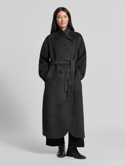 Frauenmodel trägt Mantel mit Schalkragen von Emporio Armani, dunkle Farbe, taillierte Passform, doppelte Knopfleiste, Taillienband, Ganzkörperansicht von vorne.