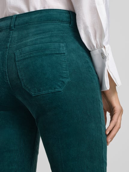 Frauenmodel trägt Cordhose mit aufgesetzten Leistentaschen von Christian Berg Woman in Grün, Baumwoll-Mix, Detailaufnahme Rückansicht.