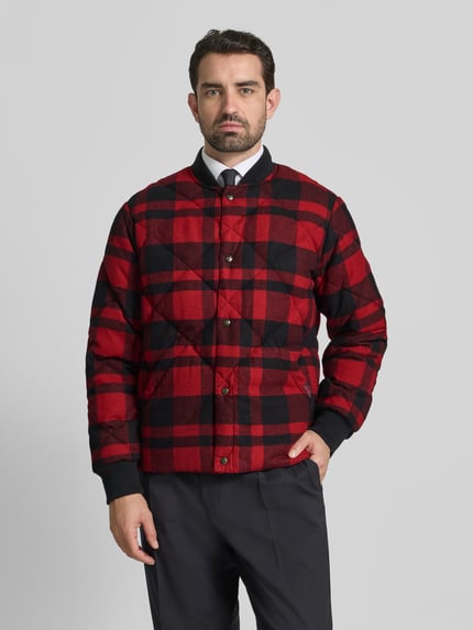 Männermodel trägt Daunenjacke mit Druckknopfleiste von Polo Ralph Lauren, rot-schwarz kariert, Baumwoll-Mix, Regular Fit, Ganzkörperansicht von vorne.