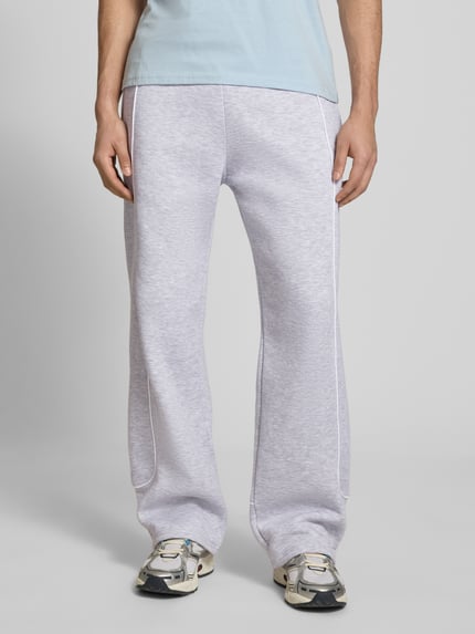 Mannenmodel draagt Sweatpants mit elastischem Bund und Logo van REVIEW van puur katoen in relaxed fit in grijs, binnenbeenlengte 78 cm, ganzkörperaanzicht van voren.