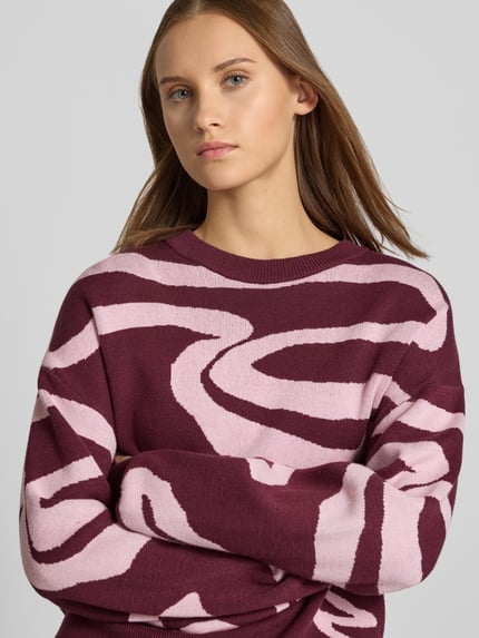 Frauenmodel trägt Relaxed Fit Pullover aus Viskose-Mix Modell 'Charlott' von NOISY MAY®, Animal-Print in Bordeaux und Rosa, Nahaufnahme Oberkörper.