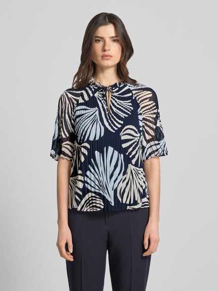 Vrouwenmodel draagt Regular Fit Blusenshirt in plissé-look van s.Oliver BLACK LABEL, all-over motief, kraag met ruches, druppelvormige hals, vetersluiting, korte mouw, ganzekijk van voren