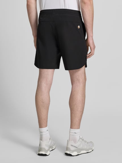 Mężczyzna nosi czarne spodenki o kroju regular fit Regular Fit Sportshorts mit Logo-Details model 'SH_TOC GAME 8 INCH' od BOSS Green, gładka tekstura, widok całej sylwetki z tyłu.