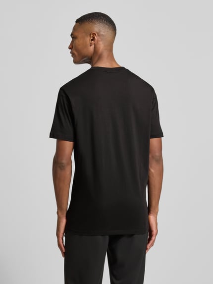 Männermodel trägt T-Shirt mit Motiv-Print von ARMANI EXCHANGE aus reiner Baumwolle, Regular-Fit, schwarze Farbe, Ganzkörperansicht Rückansicht.
