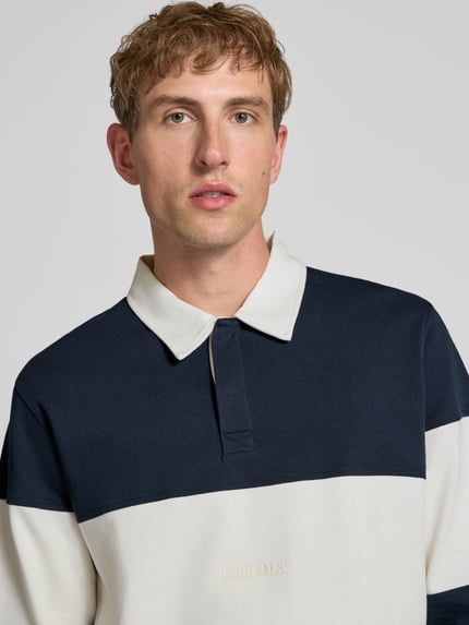Männermodel trägt Regular Fit Poloshirt mit Label-Stitching Modell 'FREDERIKSBERG' von JACK & JONES im Colour-Blocking-Design, Nahaufnahme Oberkörper, reine Baumwolle