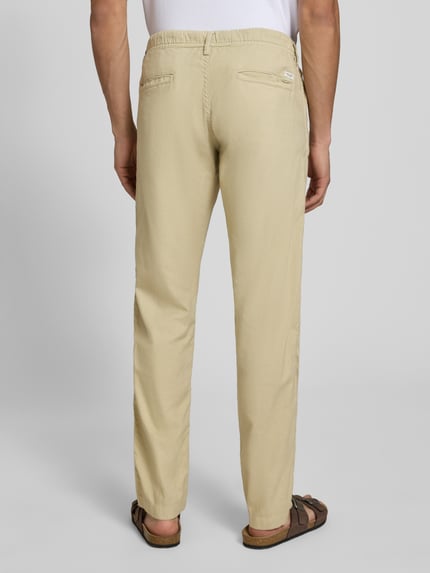 Männermodel trägt Relaxed Fit Hose aus Baumwoll-Leinen-Mix Modell 'KANE' von Jack & Jones in Beige mit elastischem Bund und Gesäßtaschen, Ganzkörperansicht Rückansicht.