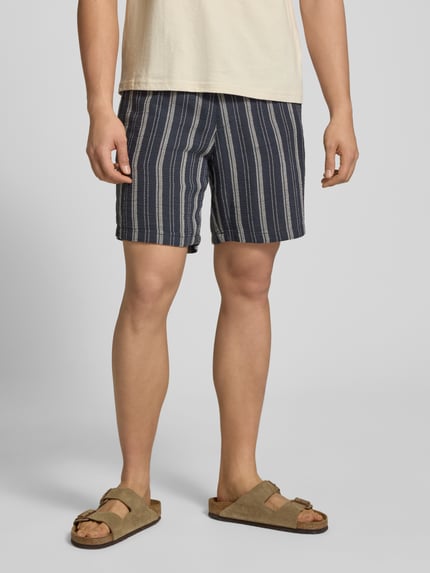 Männermodel trägt Shorts mit elastischem Bund und Logo-Detail von REVIEW, dunkle Streifen, Baumwoll-Mix, Regular-Fit, Nahaufnahme Oberschenkel.
