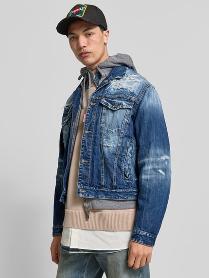 Męski model nosi Jeansjacke mit Kapuze od Dsquared2, niebieska kurtka jeansowa, elastyczna mieszanka bawełny, krój regular fit, kieszenie na piersi, kaptur z tunelem, listwa guzikowa, długość tyłu w rozmiarze M: 61 cm, szerokość ramion w rozmiarze M: 52 cm, długość rękawów w rozmiarze M: 66 cm, zdjęcie w ujęciu całej sylwetki od przodu.