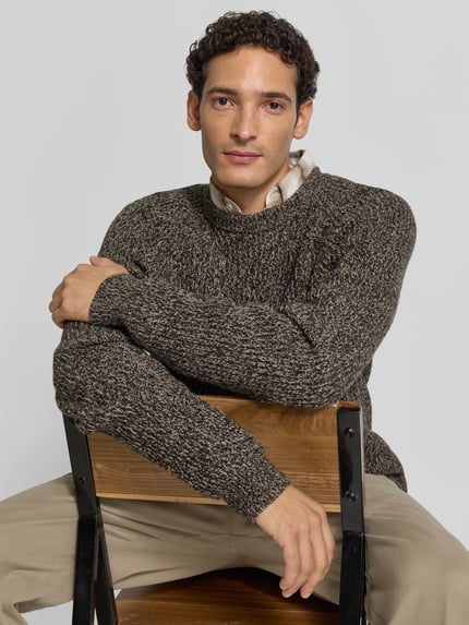 Męski model nosi sweter z dzianiny 'Strickpullover in melierter Optik' od Christian Berg Men, prosty krój, efekt melanżu, okrągły dekolt, raglanowe rękawy, długość tyłu w rozmiarze M 76 cm, długość rękawów w rozmiarze M 91 cm, stonowane kolory, tekstura melanżu, zbliżenie na górną część ciała.