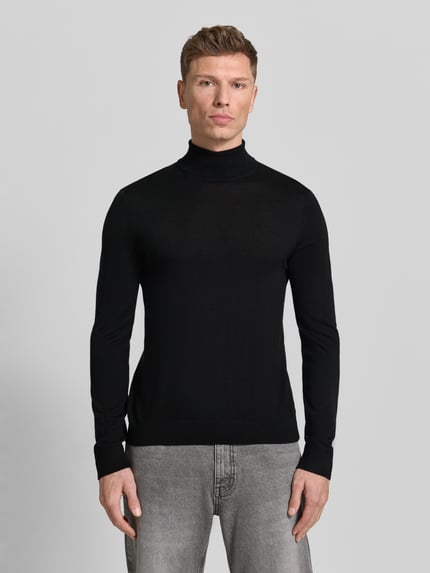 Männermodel trägt Rollkragenpullover aus Merinowolle Modell 'TRAY' von SELECTED HOMME, schwarz, körpernaher Schnitt, Ganzkörperansicht von vorne.