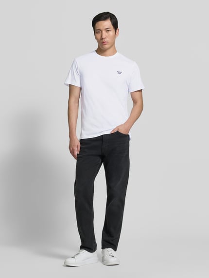 Männermodel trägt T-Shirt mit Logo-Patch und Rundhalsausschnitt von Emporio Armani, Reine Baumwolle, Modern Fit, Rückenlänge 69 cm, Ganzkörperansicht von vorne.