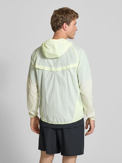 Männermodel trägt Trainingsjacke mit Logo-Print und Kapuze von NIKE TRAINING in hellem Gelb, glatte Textur, Rückansicht, Ganzkörperansicht. Gerader Schnitt, Reißverschluss, Kapuze, Rückenlänge 71 cm, Ärmellänge 66 cm.