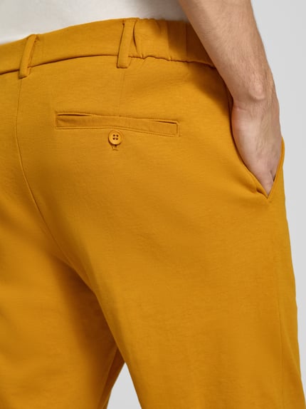 Männermodel trägt Straight Fit Chino mit Gesäßtaschen Modell 'SAMUEL' von CHILL PILL, gelb, Baumwoll-Mix, Nahaufnahme Rückansicht.