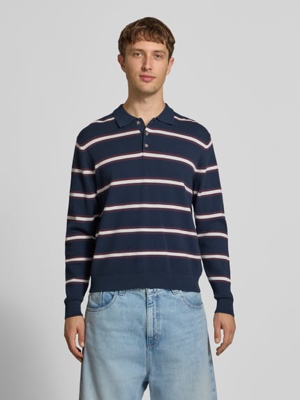 Męski model nosi Langarm-Poloshirt aus Viskose-Mix im Allover-Look von JACK & JONES, krój regular fit, Listwa guzikowa, mieszanka wiskozy, bluzka z długim rękawem, wzór na całej powierzchni, Długość tyłu w rozmiarze M: 63 cm, widok na całe ciało z przodu.