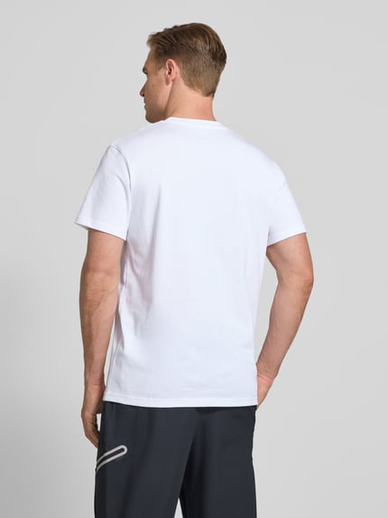 Męski model nosi Regular Fit T-Shirt mit Logo-Applikation von Under Armour z mieszanki bawełny, okrągły dekolt, długość tyłu 73 cm, Ganzkörperansicht Rückansicht.