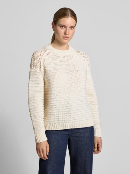 Frauenmodel trägt Strickpullover aus Wolle mit Rundhalsausschnitt von Closed in Creme, grob gestrickte Struktur, Ganzkörperansicht von vorne.