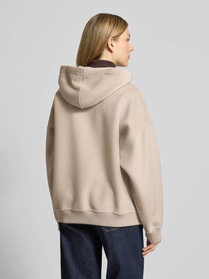 Frauenmodel trägt Oversized Sweatjacke mit Kapuze Modell 'DUNSTONE' von Drykorn in Beige, Woll-Mix, gerippte Abschlüsse, Rückansicht Ganzkörperansicht.