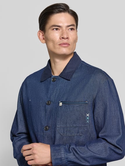 Männermodel trägt Regular Fit Hemdjacke in Denim-Optik von Scotch & Soda, reine Baumwolle, Kentkragen, Nahaufnahme Oberkörper.