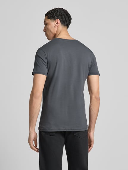 Männermodel trägt T-Shirt mit Label-Details Modell 'BASIC' von Alpha Industries, Reine Baumwolle, Gerader-Schnitt, Rückenlänge 67 cm, Ganzkörperansicht Rückansicht.