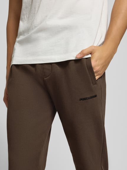 Männermodel trägt Sweatpants mit elastischem Bund von Pegador, Baumwoll-Mix, Label-Stitching, lockerer Schnitt, Nahaufnahme Oberkörper.
