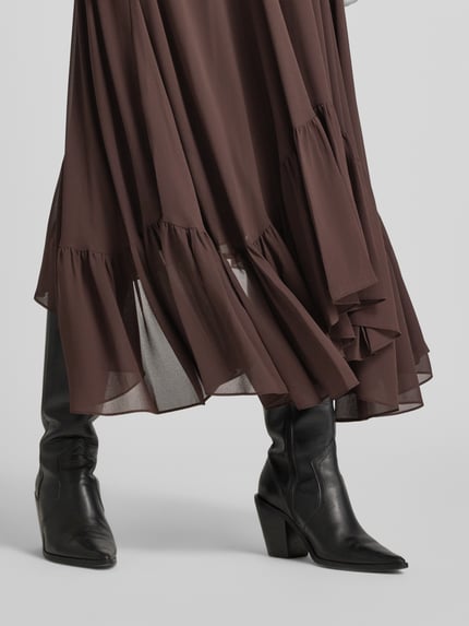 Frauenmodel trägt Midi-Rock aus Chiffon in asymmetrischem Look von MICHAEL Michael Kors, brauner A-Linien-Stoff, Detailaufnahme, Damen Midi-Rock, Chiffon, elastischer Bund, Bundweite 34 cm, Länge 97 cm.