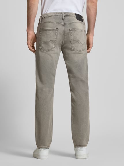 Męski model nosi Regular Fit Jeans im Used-Look Modell 'CLARK' von JACK & JONES z mieszanki bawełny z dodatkiem streczu, wpuszczane kieszenie, krój regular fit, efekt znoszenia, szerokość w rozmiarze 32/32: 42 cm, długość wewnętrzna nogawki 75 cm, widok całej sylwetki z tyłu.