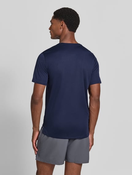 Męskimodel nosi t-shirt z nadrukiem z logo Model 'CORE' od ASICS TIGER, prosty krój, okrągły dekolt, długość tyłu w rozmiarze M: 72 cm, widok całej sylwetki z tyłu