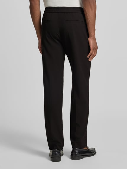 Männermodel trägt Relaxed Fit Sweatpants mit Viskose-Anteil von Lindbergh, Schwarz, Elastischer-Material-Mix, Bügelfalten, Ganzkörperansicht Rückansicht. Bundweite in Größe M beträgt 41 cm, Innenbeinlänge 79 cm.