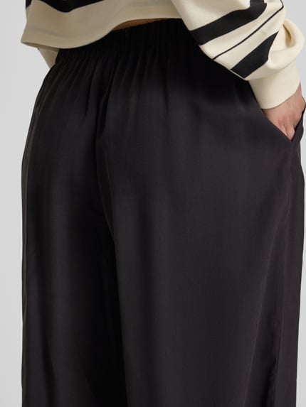 Frauenmodel trägt Loose Fit Weite Hose mit elastischem Bund Modell 'SCARLY' von Only, unifarben, Nahaufnahme Rückansicht.