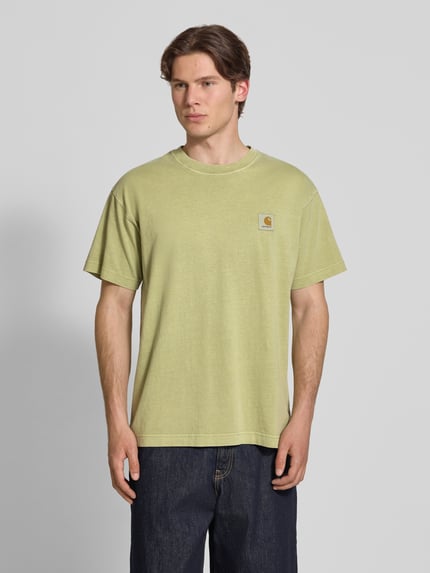 Männermodel draagt T-shirt met labeldetail model 'Nelson' van Carhartt Work In Progress, puur katoen, relaxed fit, ronde hals, ruglengte bij maat M 72 cm, lichte groentint, rechte lijnen, zachte textuur, heren T-shirt. Ganzkörperansicht van voren.