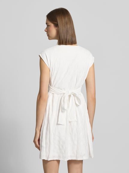 Vrouwenmodel draagt Kurzes Kleid mit V-Ausschnitt, Lochstickerei und großer Schleife van REVIEW, wit, materiaalmix met stretch, A-lijn, ajourwerk, grote strik, ruglengte in maat S 84 cm, borstwijdte 42 cm, volledig zichtbaar van achteren