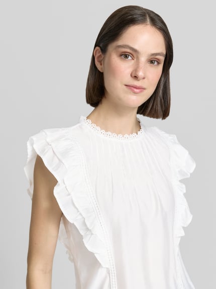Frauenmodel trägt Regular Fit T-Shirt aus Viskose-Mix Modell 'BLISS' von Vero Moda, weiß, Rüschen, Popeline, Nahaufnahme Oberkörper.