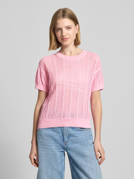 Kobiece model nosi Relaxed Fit Strick-Shirt aus Baumwoll-Mix Modell 'LUX LIGHT' von Vero Moda, efekt: jednolity kolor, ażurowy wzór, okrągły dekolt, krótki rękaw, prążkowane zakończenia, mieszanka bawełny, dzianina ażurowa, jasnoróżowy, tekstura przewiewna, gładkie wykończenia, widok całej sylwetki z przodu.