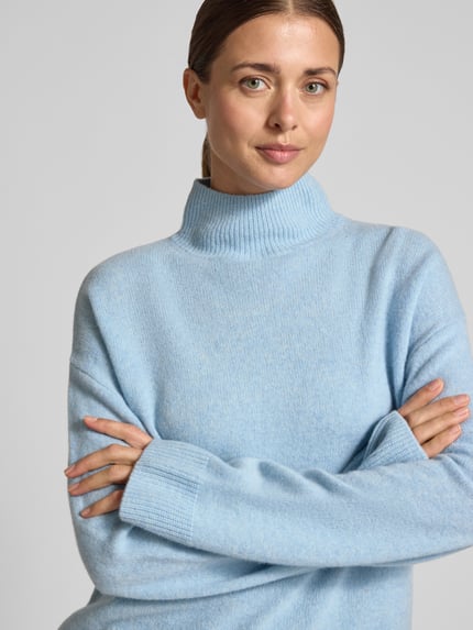 Frauenmodel trägt Strickpullover mit Stehkragen von Christian Berg Woman in hellblau mit weiter Passform, reine Baumwolle, Nahaufnahme Oberkörper.